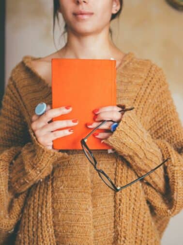 Image of woman holding a book representing The Stories We Loved As Children Contain Clues for Our Soul.