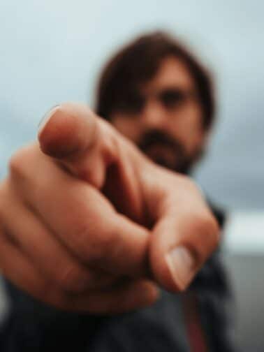 A blurry image of a man pointing aggressively, representing How to Spot a Sociopath. (And How to Protect Yourself From Them)