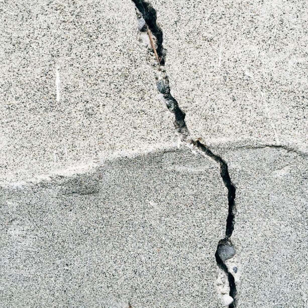 Crack on cement wall, paint, covering graffiti representing the foundational damage of early relational trauma