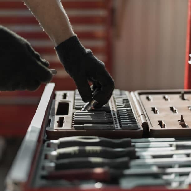 Mechanic in gloves taking tools and instruments out of a chest representing the biopsychosocial basics In a relational trauma self-care tool chest