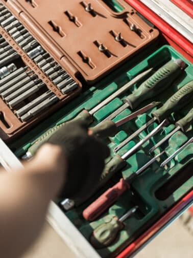 Crop shot of worker in gloves taking screwdriver out of toolset in cabinet drawer representing emotional regulation tools