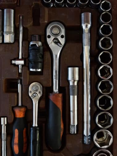 From above closeup view of various socket wrenches with ratchet lying in toolbox with metal handles representing coping tools in a self care tool chest.