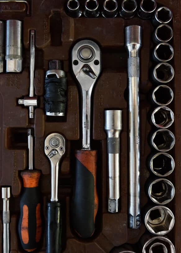 From above closeup view of various socket wrenches with ratchet lying in toolbox with metal handles representing coping tools in a self care tool chest.