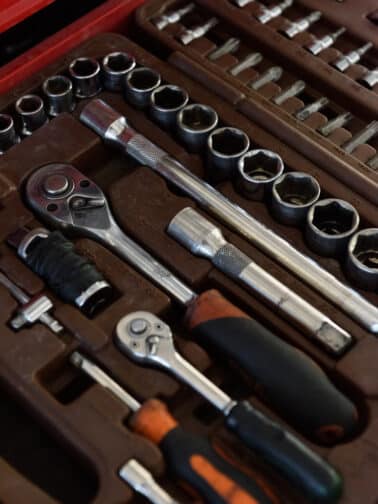 Closeup shot of shiny metal wrenches and ratchets with handles lying in special toolkit representing our resilience tools in a self-care tool chest.