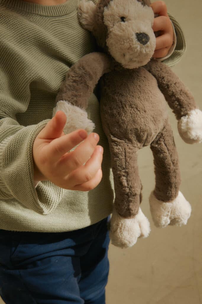 A small child holding a stuffed animal, representing the longing for safety and comfort often rooted in trauma bonding.