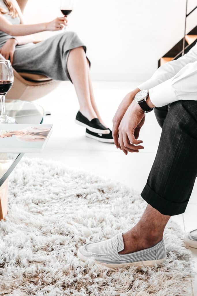 A couple sitting apart with wine glasses in hand, symbolizing emotional distance and tension within a trauma bond.