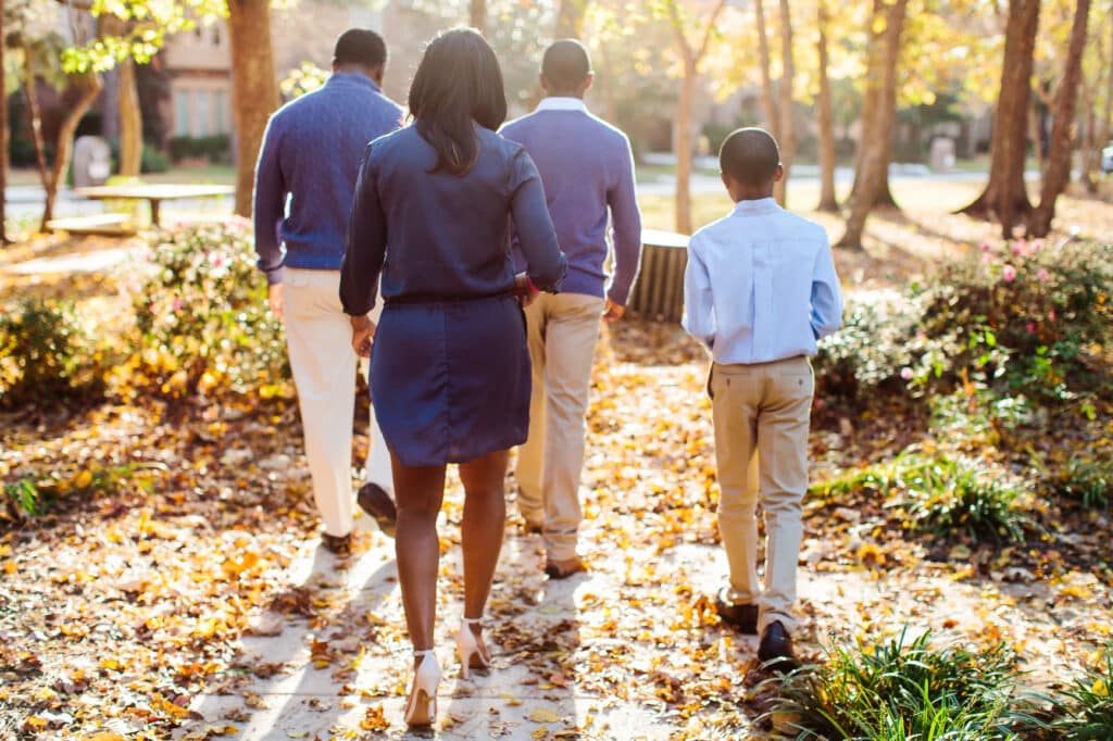 A family walks together down a sunlit path, representing connection, safety, and nervous system regulation after trauma.