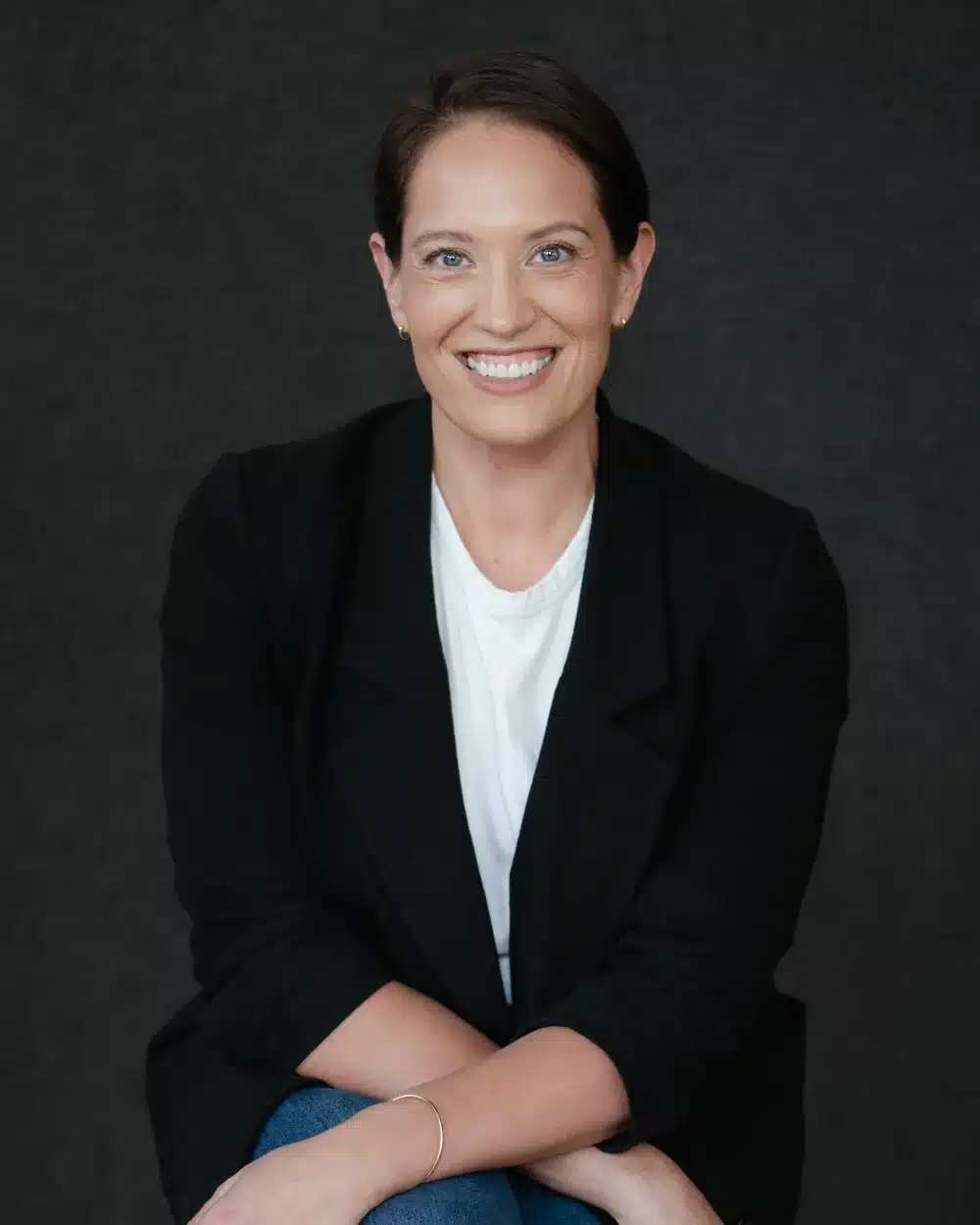 Annie Wright, LMFT, trauma therapist and executive coach, in a black blazer against a dark studio backdrop